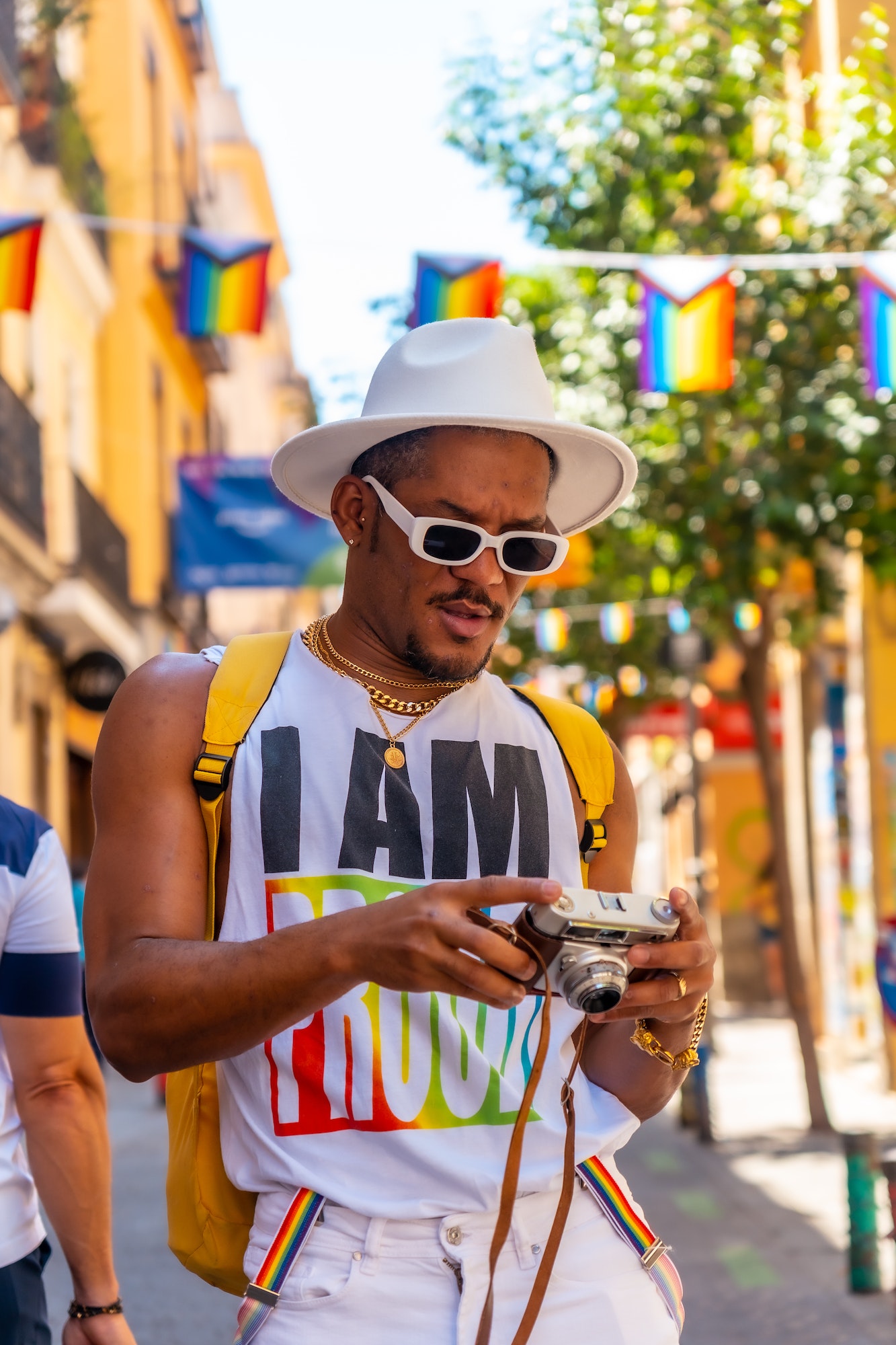 A gay black ethnicity man at the pride party looking at the photos on the camera, LGBT flag